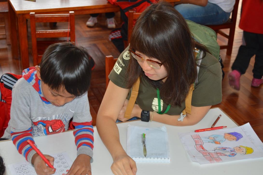 Early childhood development volunteer helps a boy color pictures as part of his homework in Peru. Projects Abroad volunteer helps her student with an early childhood development activity during her spring break in Peru.